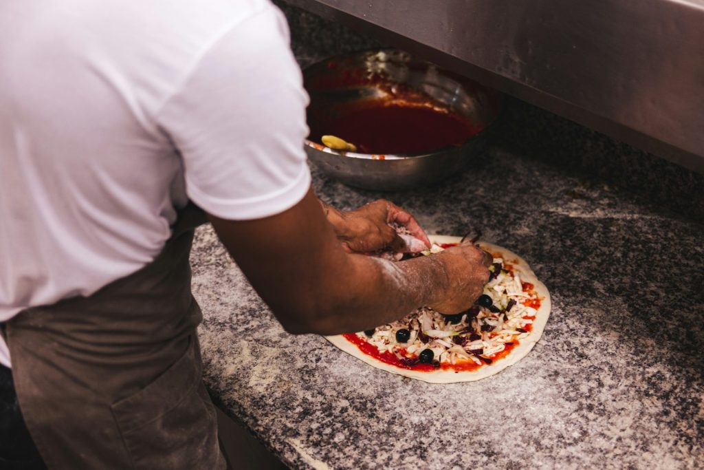 un homme préparant une pizza dans une cuisine