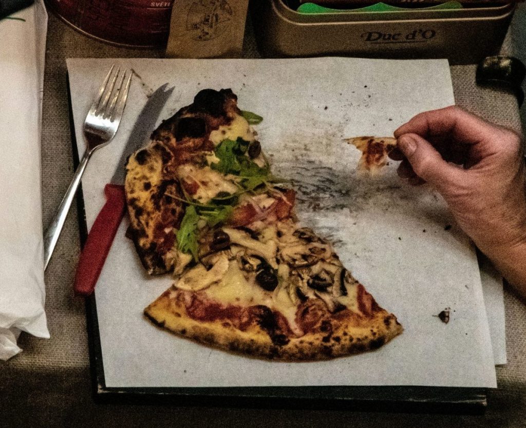 une personne mangeant une part de pizza dans une boîte