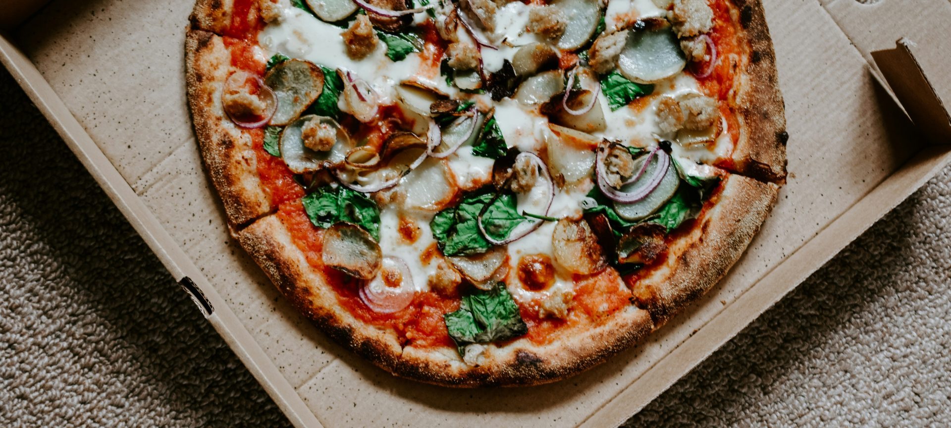 pizza avec des feuilles vertes sur une boîte brune