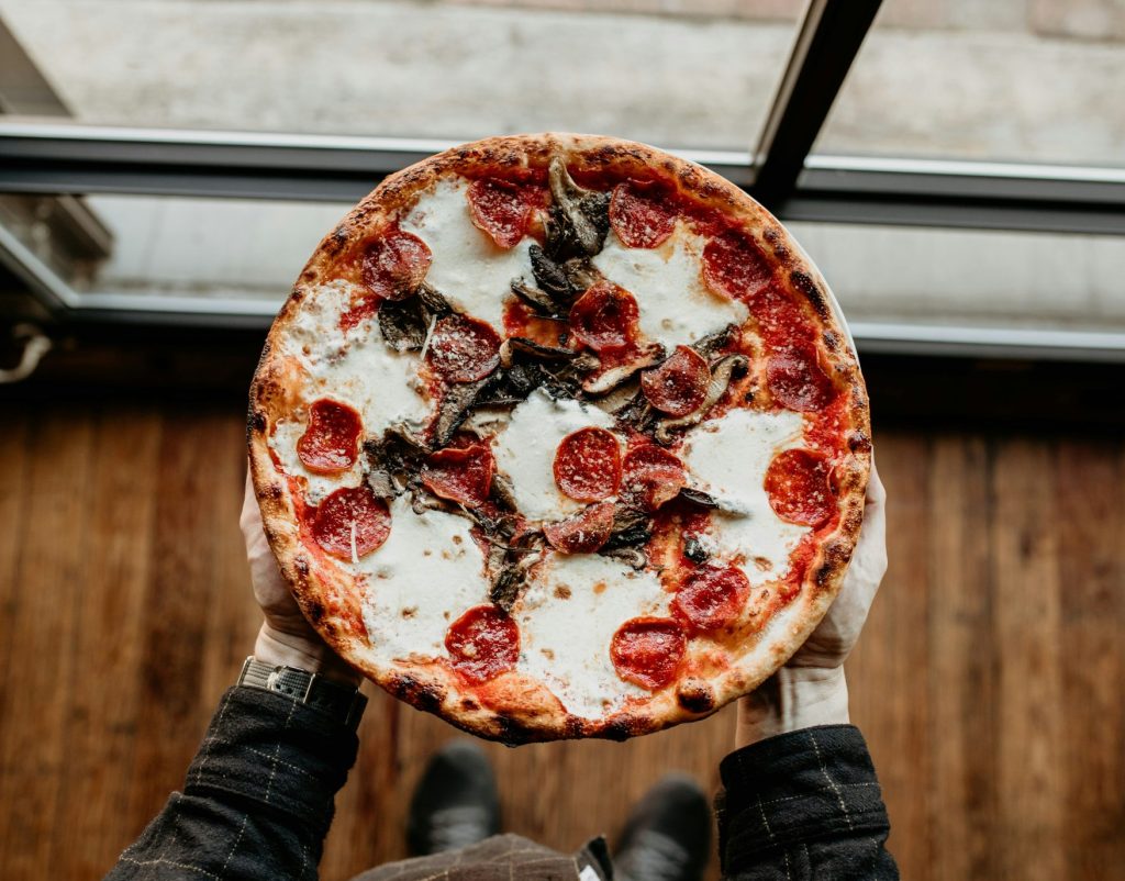 une personne tenant une pizza garnie