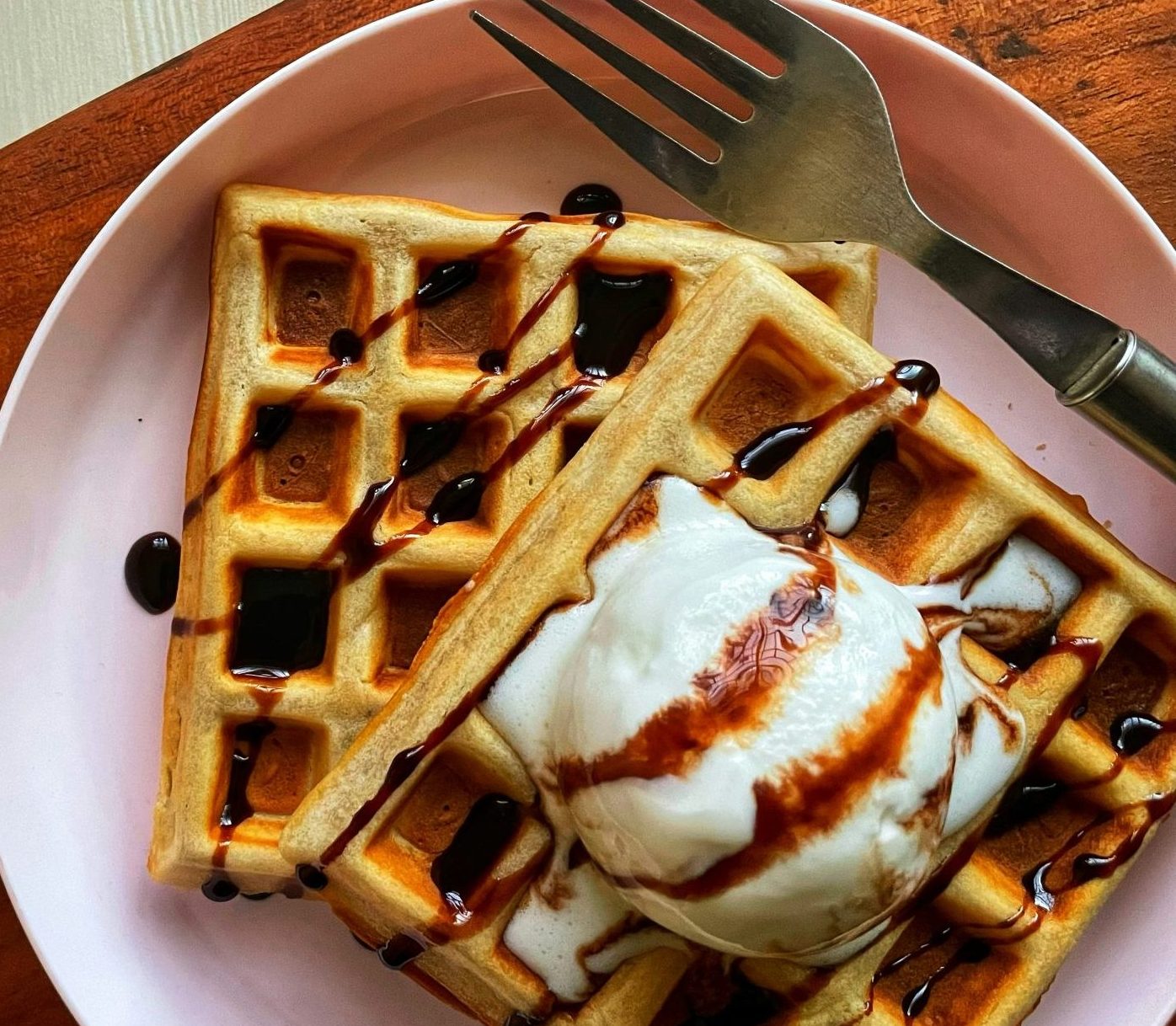 a plate of waffles with syrup and a fork