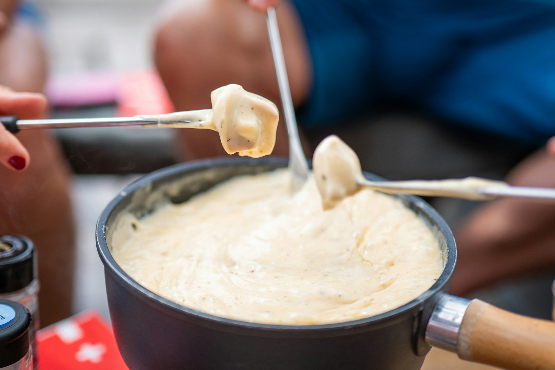 Des gens trempant du pain dans un pot de fondue au fromage.